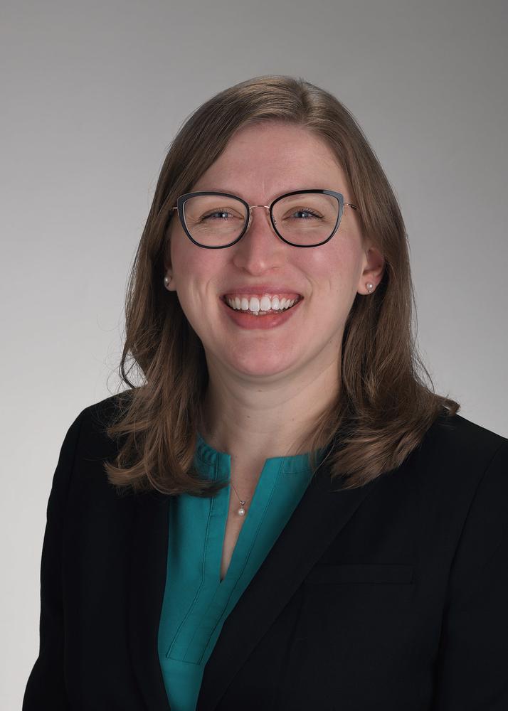 Photo of Jess Meyer smiling at camera in green shirt and black jacket