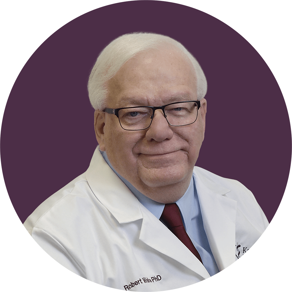 man in white doctor coat, wearing blue shirt and purple tie with a purple background in the back