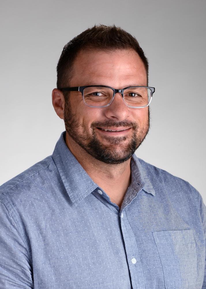 smiling man wearing glasses and a blue shirt