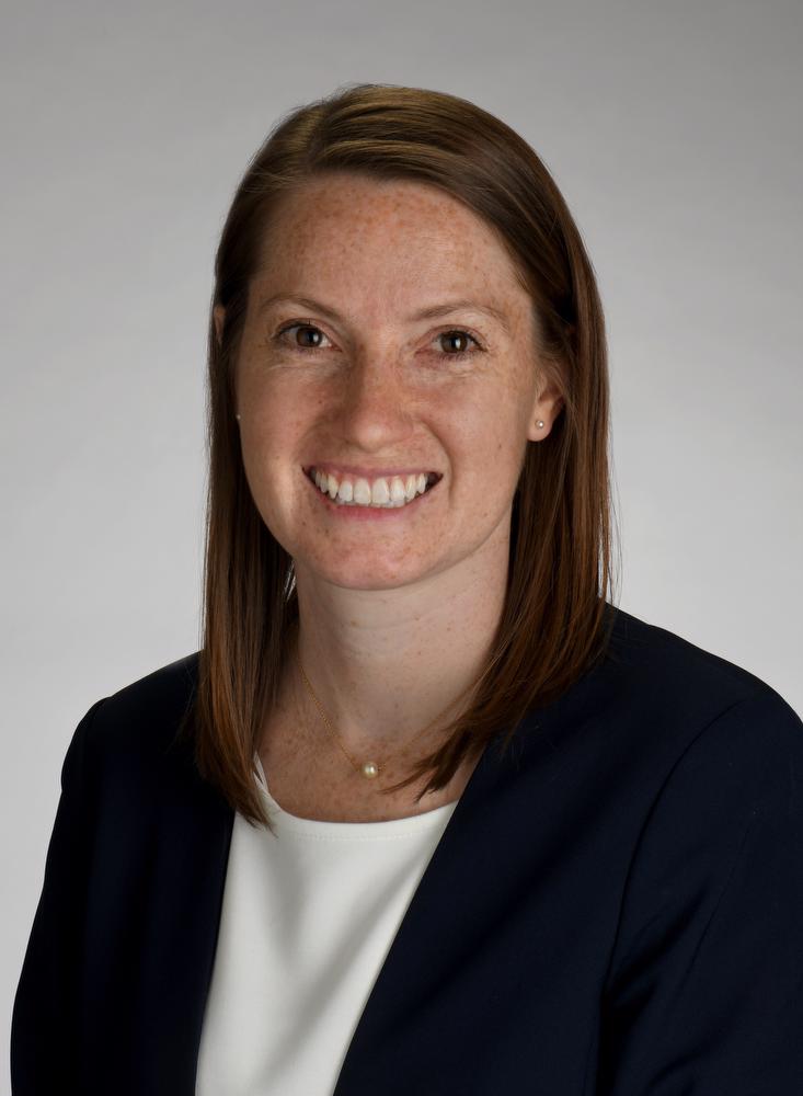 smiling woman in black jacket, white shirt with gold necklace