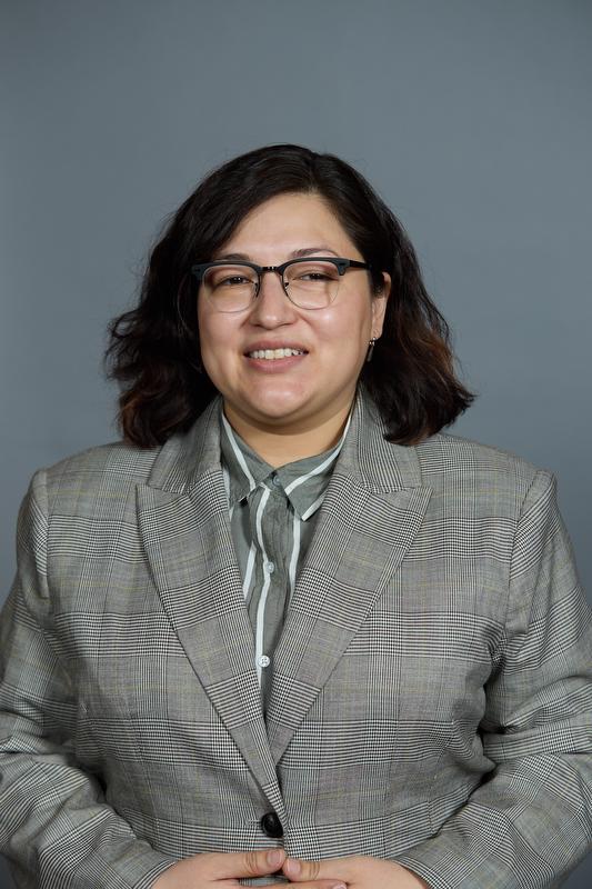 Photo of Luz Ortiz with gray striped jacket, gray and white shirt and glasses