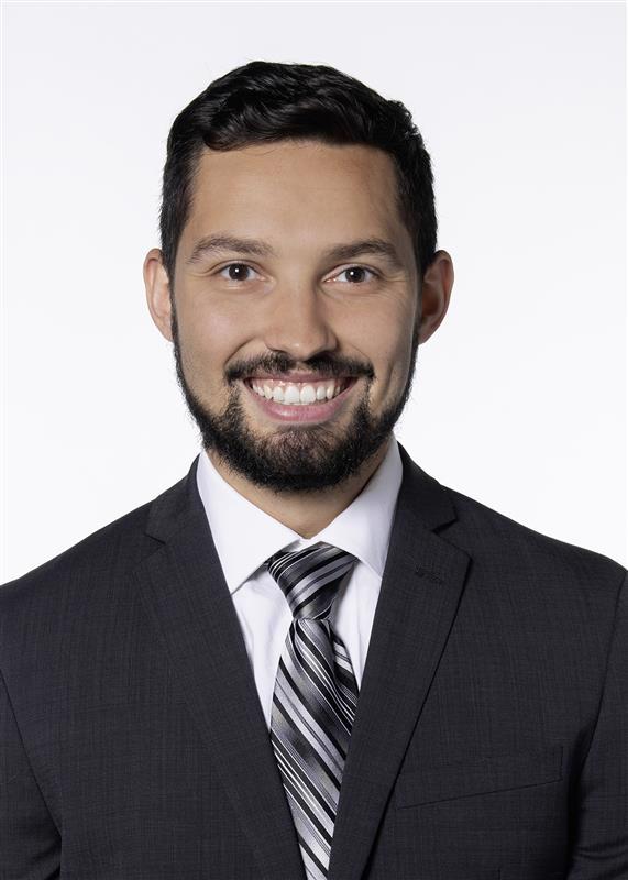 photo of smiling Chase Sakitis in black suit with black and white stripped tie
