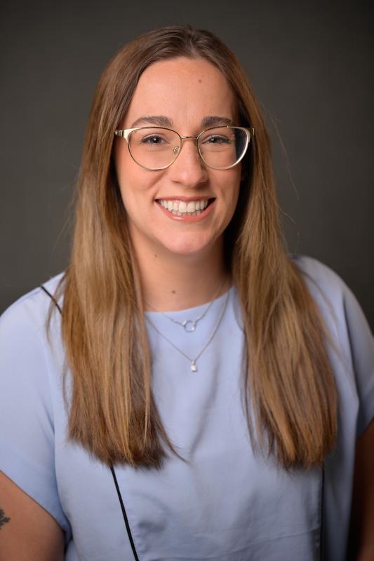 Photo of Abby Kietzman smiling at camera wearing a light purple shirt and two necklaces