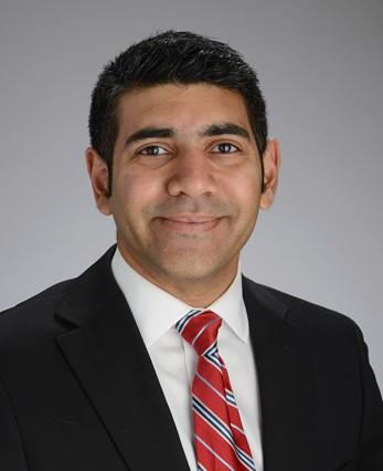 photo of Abid Qureshi, M.D. wearing a black jacket, white tie and red and black striped tie