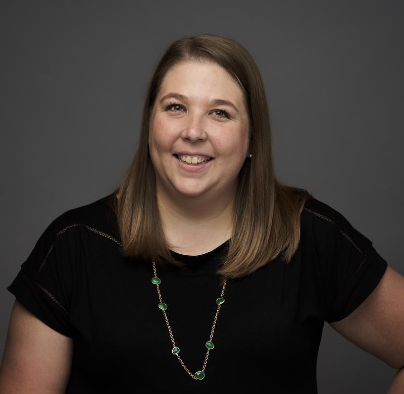 photo of smiling woman in black shirt wearing gold and green necklace
