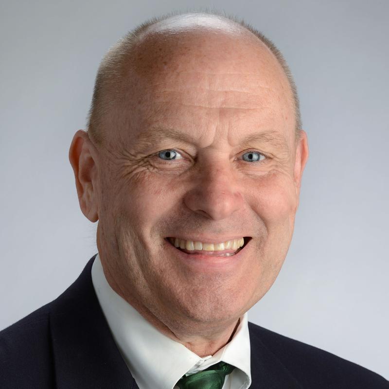 Smiling man wearing a black jacket, white shirt and green tie