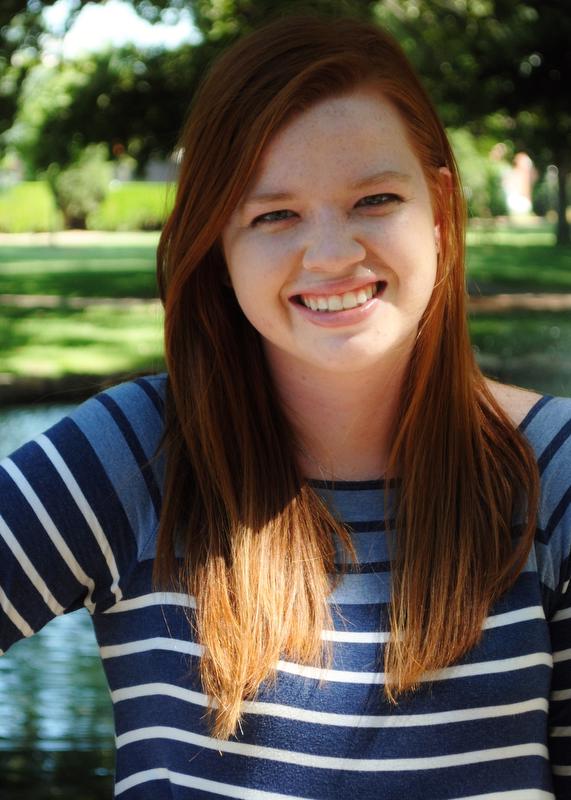 woman in blue and white striped shirt in front of lake
