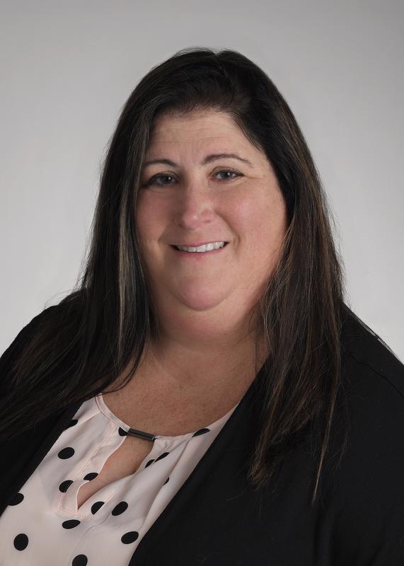 smiling woman in black jacket and pink and black polka dot shirt
