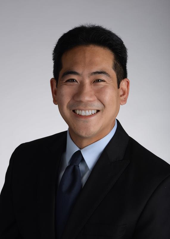 smiling man in black jacket, blue shirt and dark blue tie