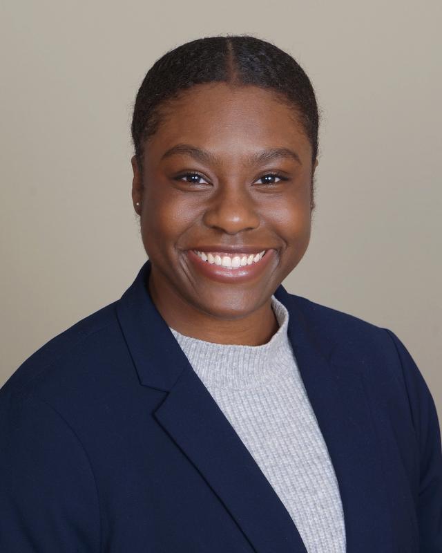 smiling woman in gray shirt wearing a dark blue blazer