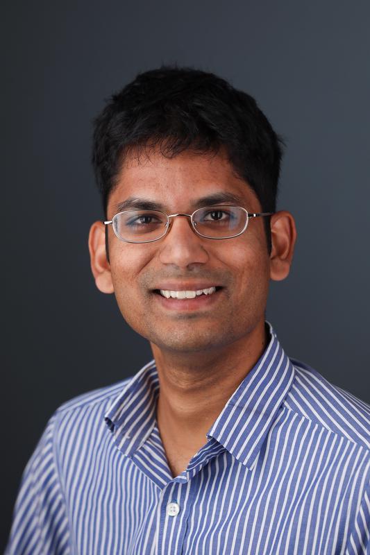 smiling man wearing glasses and blue and white striped shirt