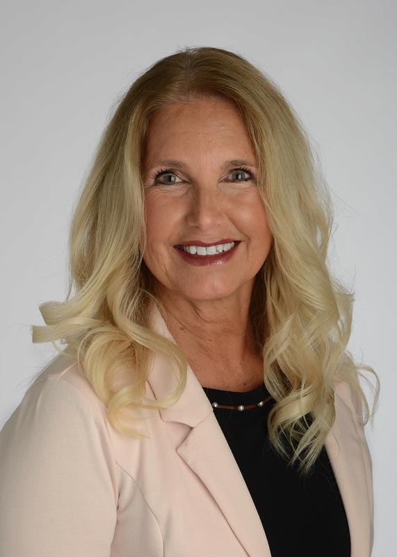 smiling woman in black shirt with light pink jacket
