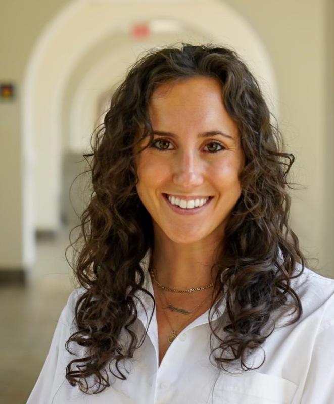 smiling woman wearing a white shirt posing in a hallway