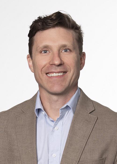 smiling man in brown jacket and blue shirt