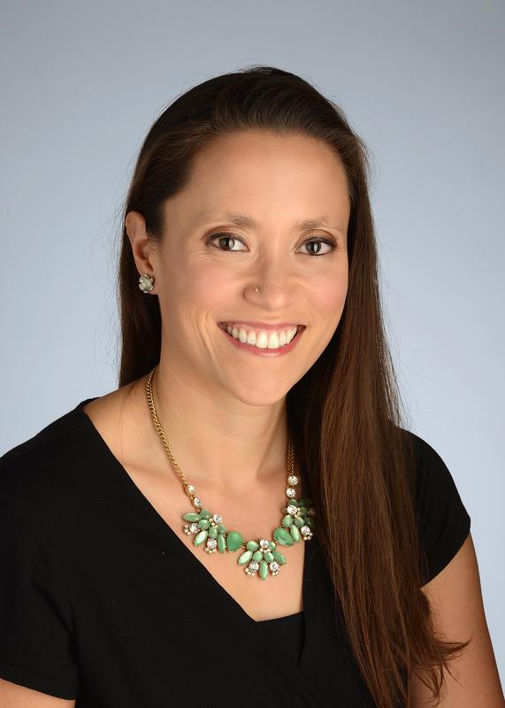 smiling woman in black shirt with large green necklace