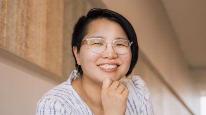 smiling woman in glasses with a white shirt with blue and black stripes