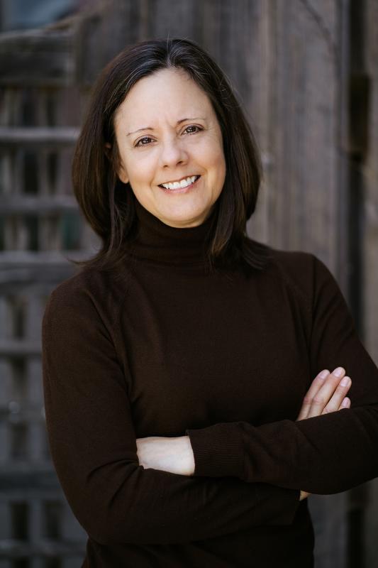 smiling woman in dark shirt with arms crossed