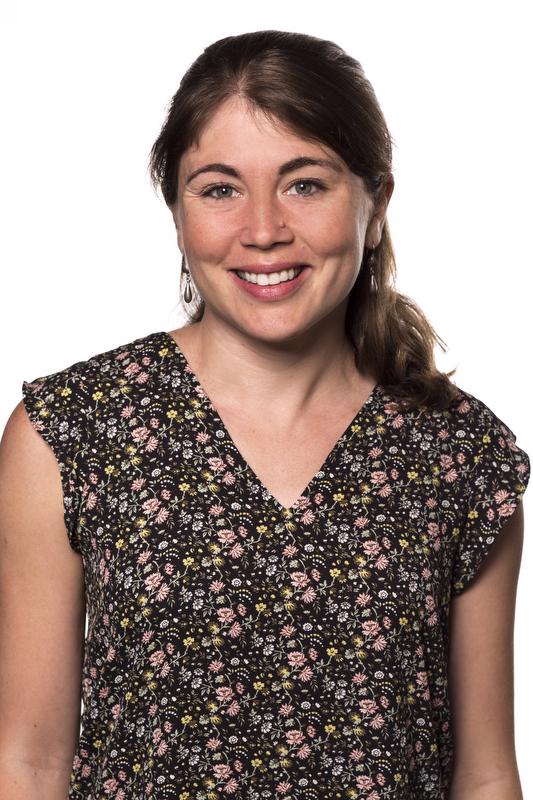 smiling woman wearing a multi-colored shirt and earrings