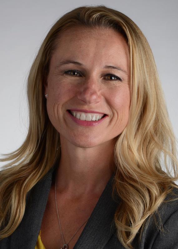 smiling woman with long hair wearing gray jacket and a necklace