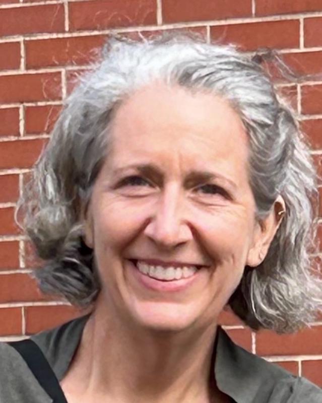 smiling woman with chin length hair wearing a gray and black shirt