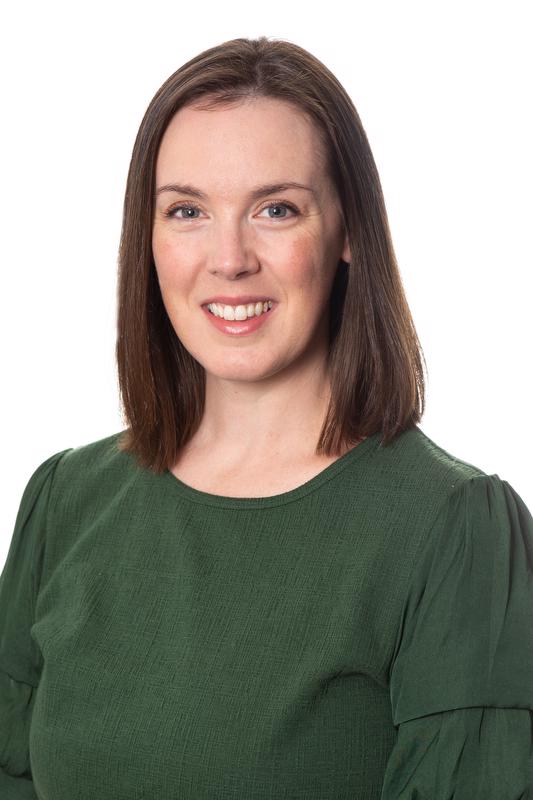 smiling woman with shoulder length hair wearing a green shirt