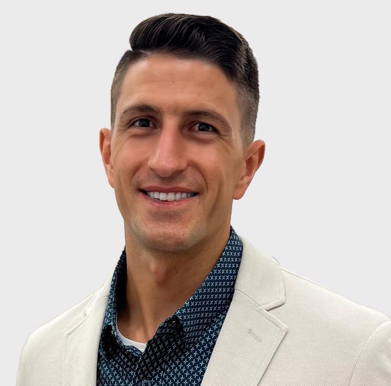smiling man in white jacket and blue with white x shirt