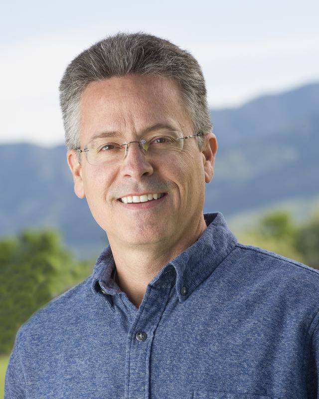 smiling man wearing a blue button down shirt and glasses