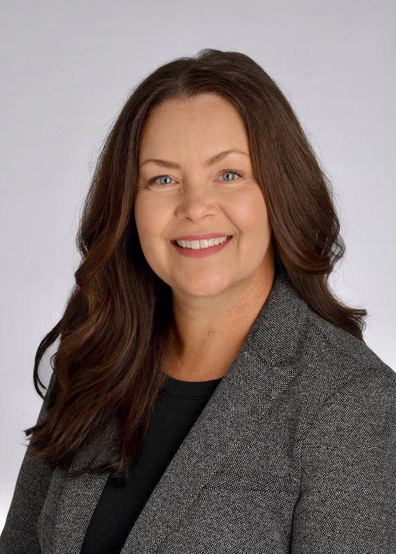 smiling woman with long hair wearing a gray jacket and black shirt