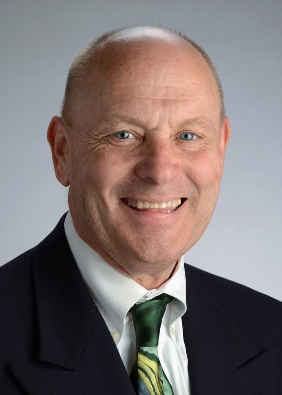 smiling man wearing a black jacket, white shirt and green tie with yellow and light green designs