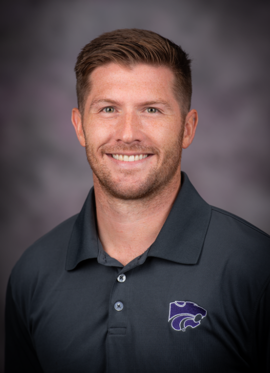 Smiling man wearing gray polo shirt with K-State logo
