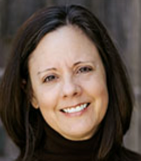 A smiling woman with shoulder-length brown hair wearing a red turtleneck shirt.
